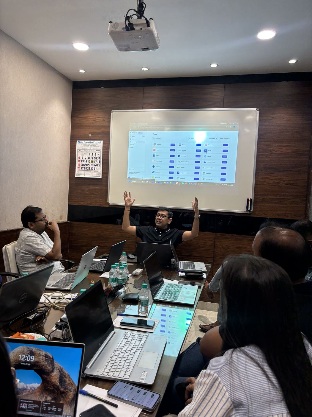 Akhil taking a question from the room, hand raised, laptops open on the table